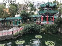 09B A hexagonal pavilion and covered colonnade walkway next to a small pond in the Good Wish Garden at Wong Tai Sin temple Hong Kong